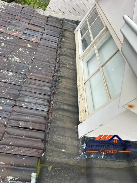 Aged apron flashing beside a dormer window on a Canterbury terracotta roof before repair