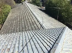 Pressure cleaning underway on a cement tile roof in Glen Waverley