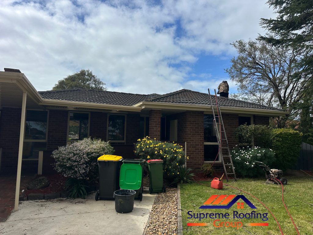Rowville home during roof pressure cleaning, with a worker and cleaning equipment visible
