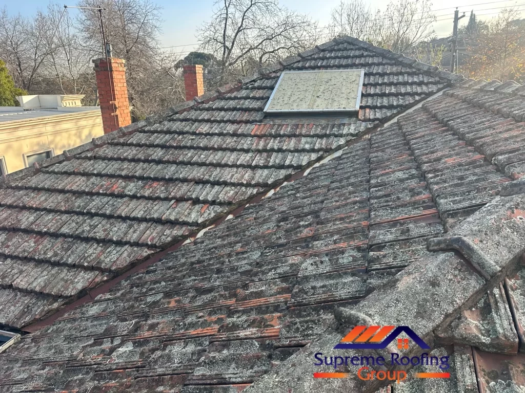 Terracotta roof slopes and valley beside a skylight before repairs